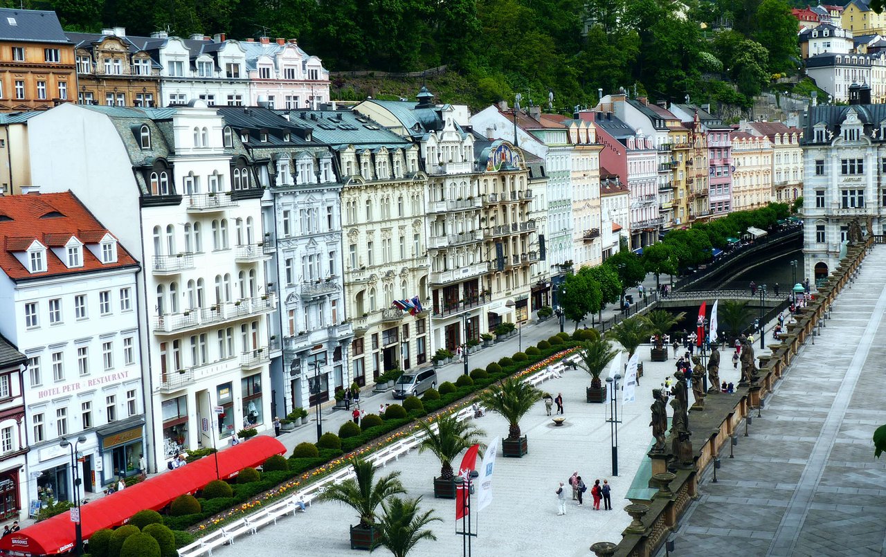 Grand historic buildings with intricate details and colorful facades line a wide pedestrian street