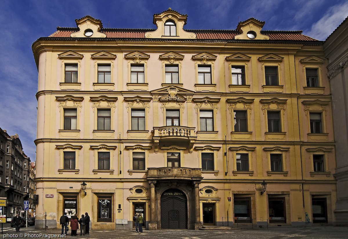 A yellow-toned building facade with four levels of aligned windows
