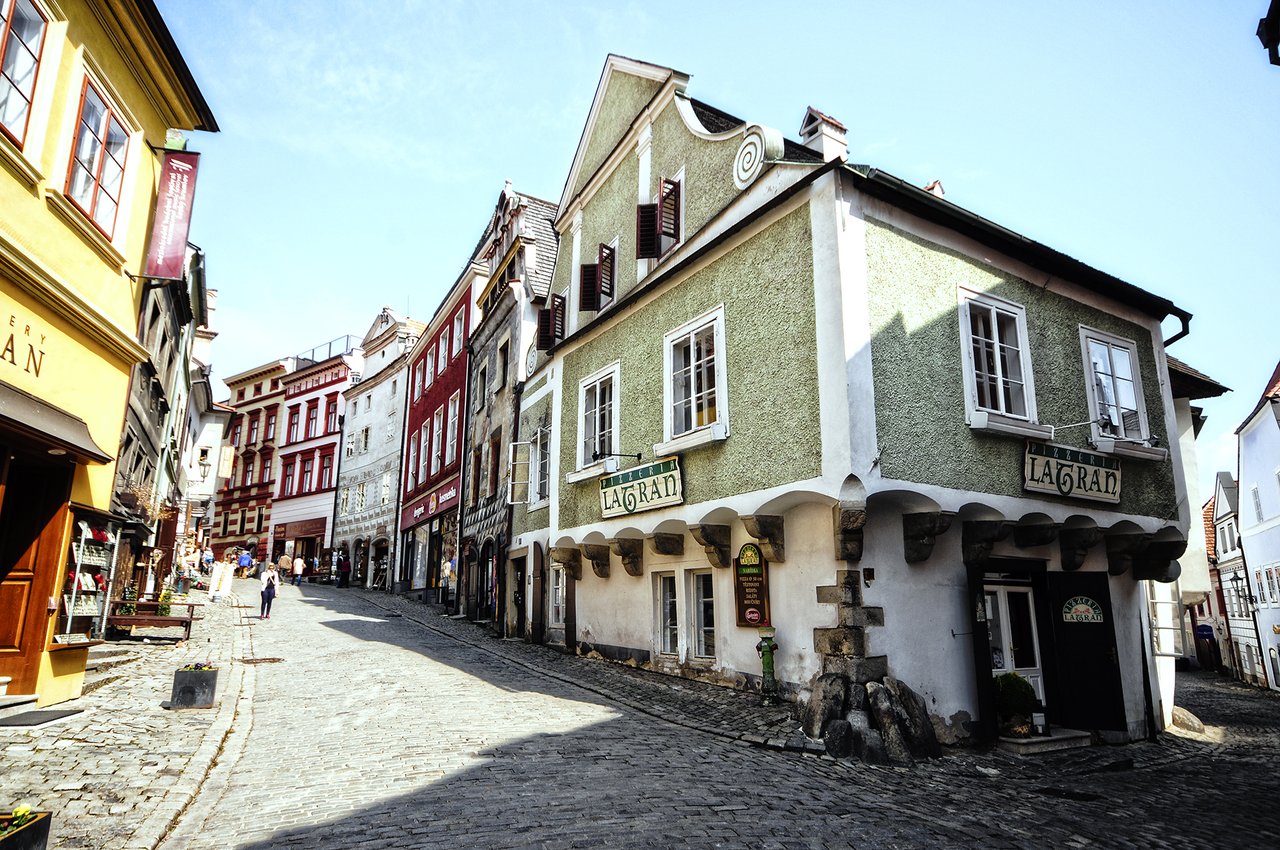A sloping cobblestone street, lined with colorful buildings, under a blue sky