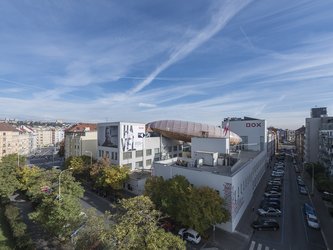 en:An aerial view of a large, airship-shaped structure perched on the roof of a building ;fr:Vue aérienne d'une grande structure en forme de bateau aérien perchée sur le toit d'un immeuble