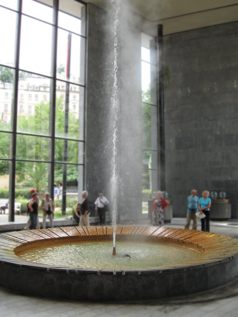 A circular fountain from which a jet of water shoots up, accompanied by smoke rising from the water