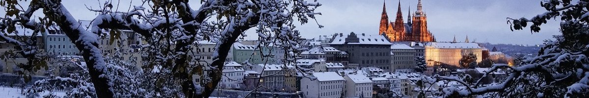View of the snow-covered city, with Prague Castle lit up in the background