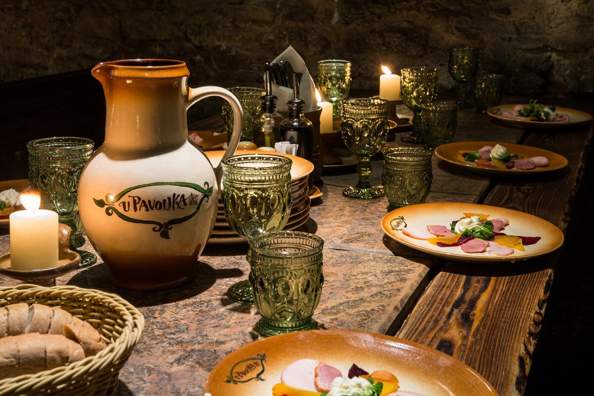 A table set with medieval glasses and plates filled with food, with a carafe in the center